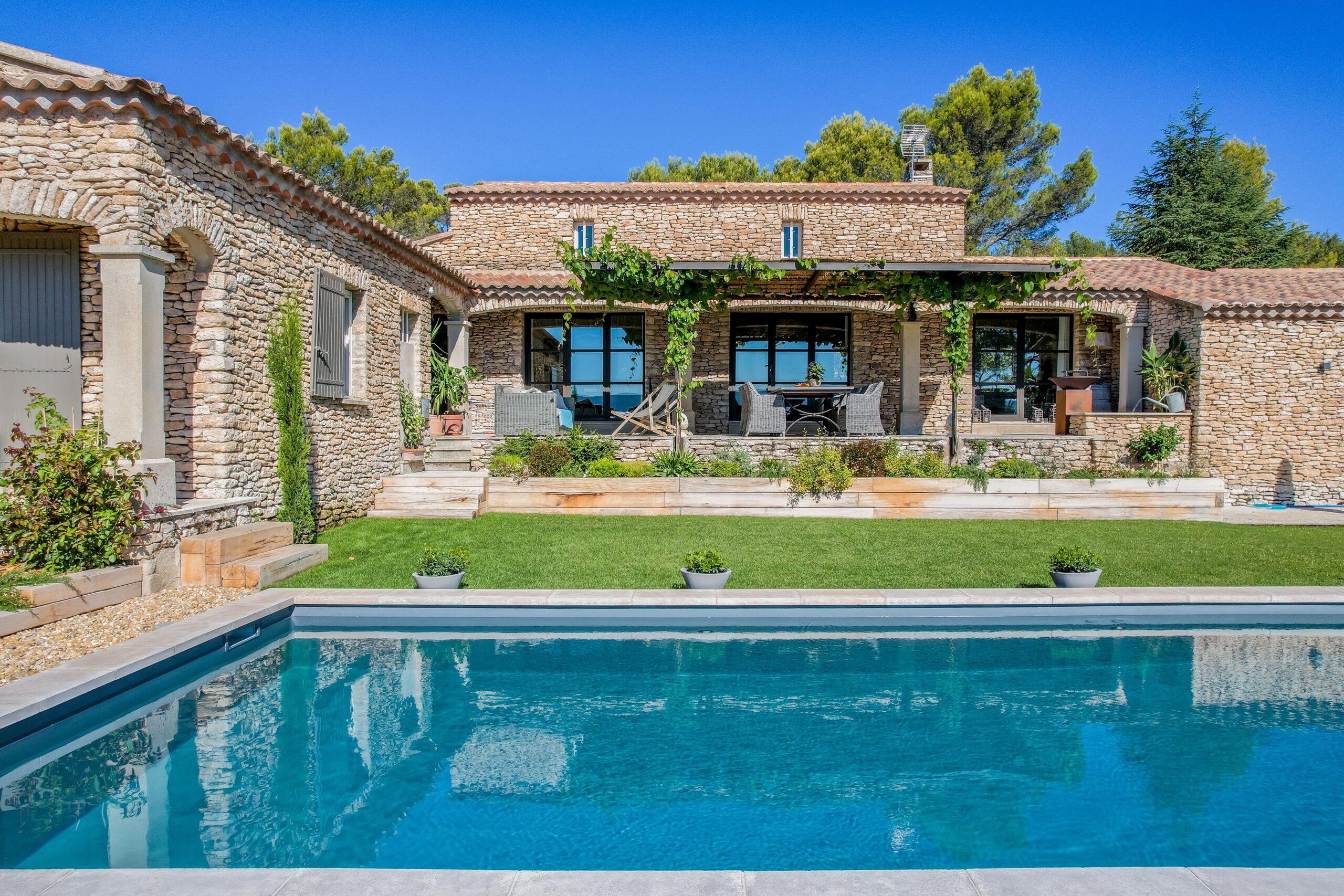 La casa in pietra, il portico e il giardino verso la piscina