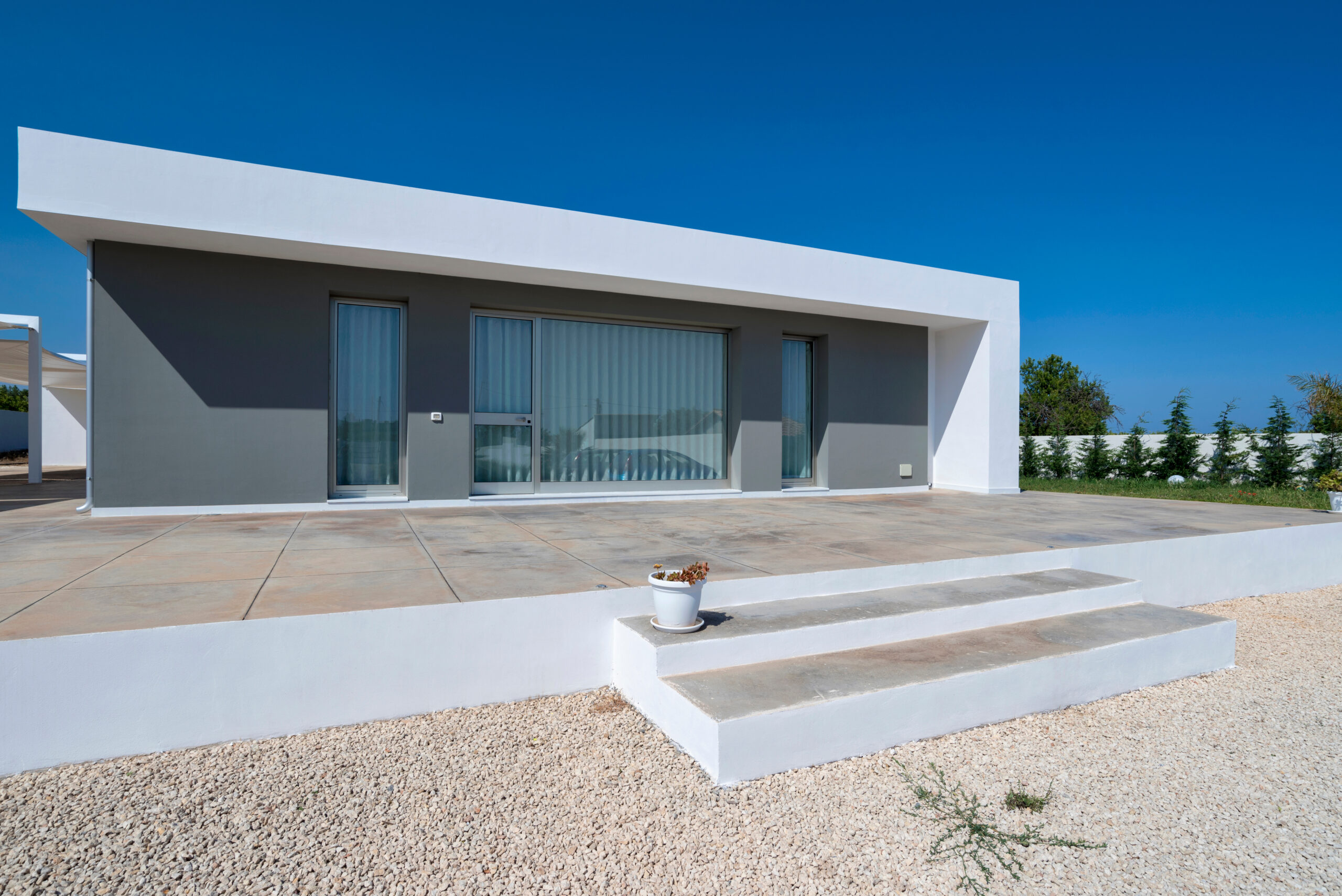 Il prospetto grigio, la cornice bianca e la terrazza d’ingresso