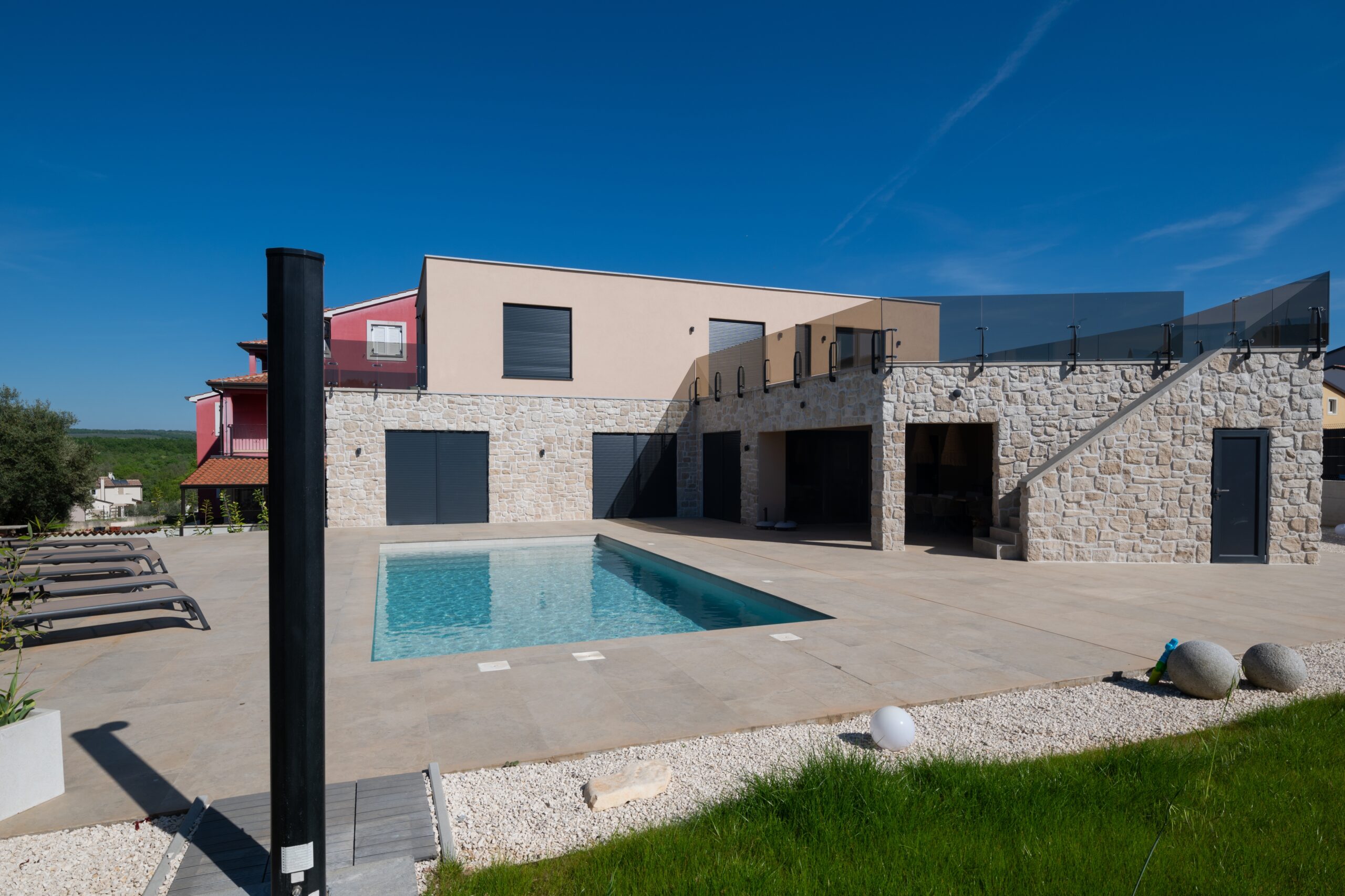 La piscina e il fronte della villa con la terrazza superiore